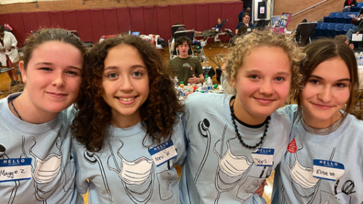 NYBC little doctor student scholarship participants. Four teenaged girls with their arms intertwined smiling at the camera.
